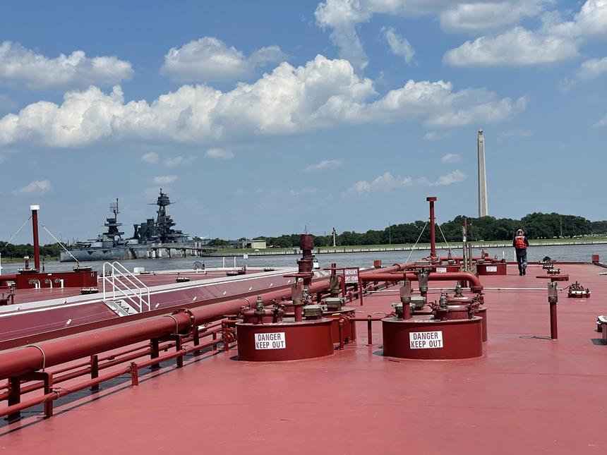 Barge deck with hatch covers on the Houston Ship Channel, San Jacinto Monument and USS Texas beyond